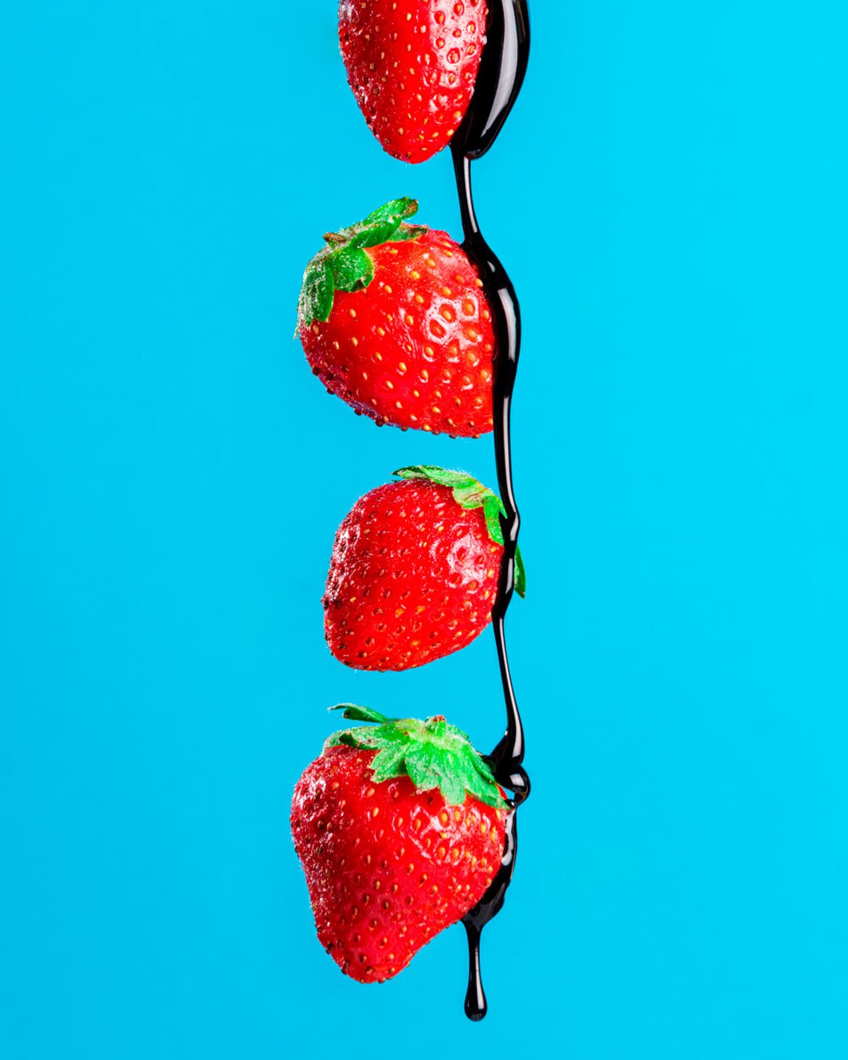 Frutilla con chocolate sobre fondo cyan — fotografía profesional